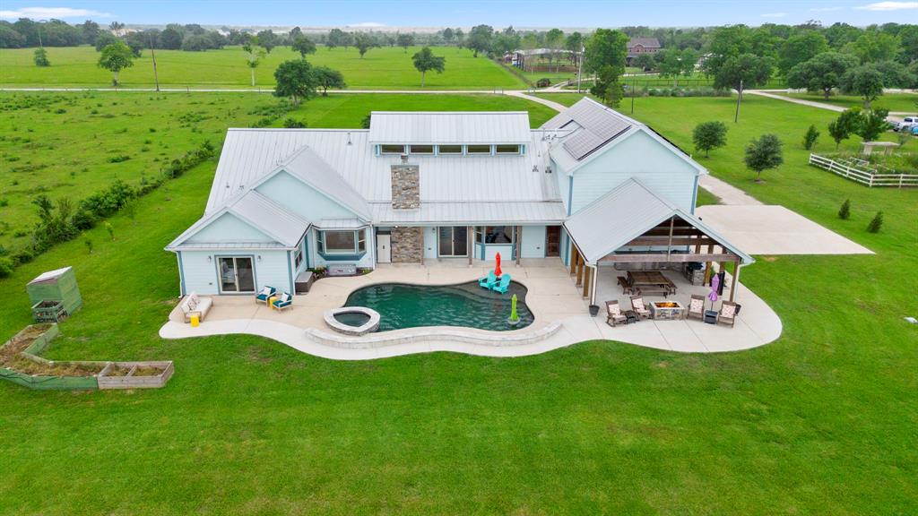 Aerial view of this fabulous home with study, huge gameroom and large workshop building located on 4.996 acres in the Mary V O'Donnell country subdivision in Brazoria County.  This wonderful "smart home" offers quiet, country living with a home equipped with modern, advanced technology and conveniences.View of back of home with its fabulous ourdoor living areas including gleaming pool/spa, outdoor kitchen, spacious covered patio and tons of patio decking surrounded by acres of gorgeous, greenspace.