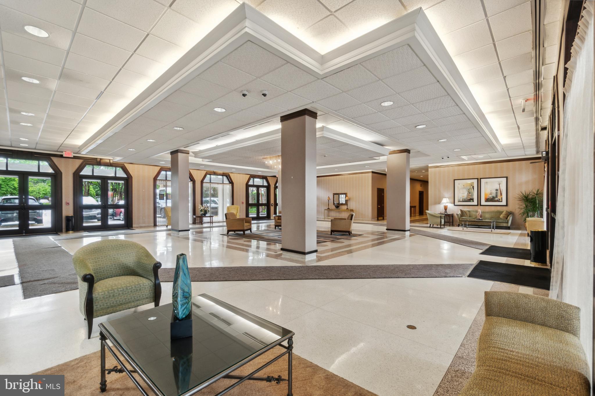 a dining hall with couches a flat tv screen and a dining table with the kitchen view