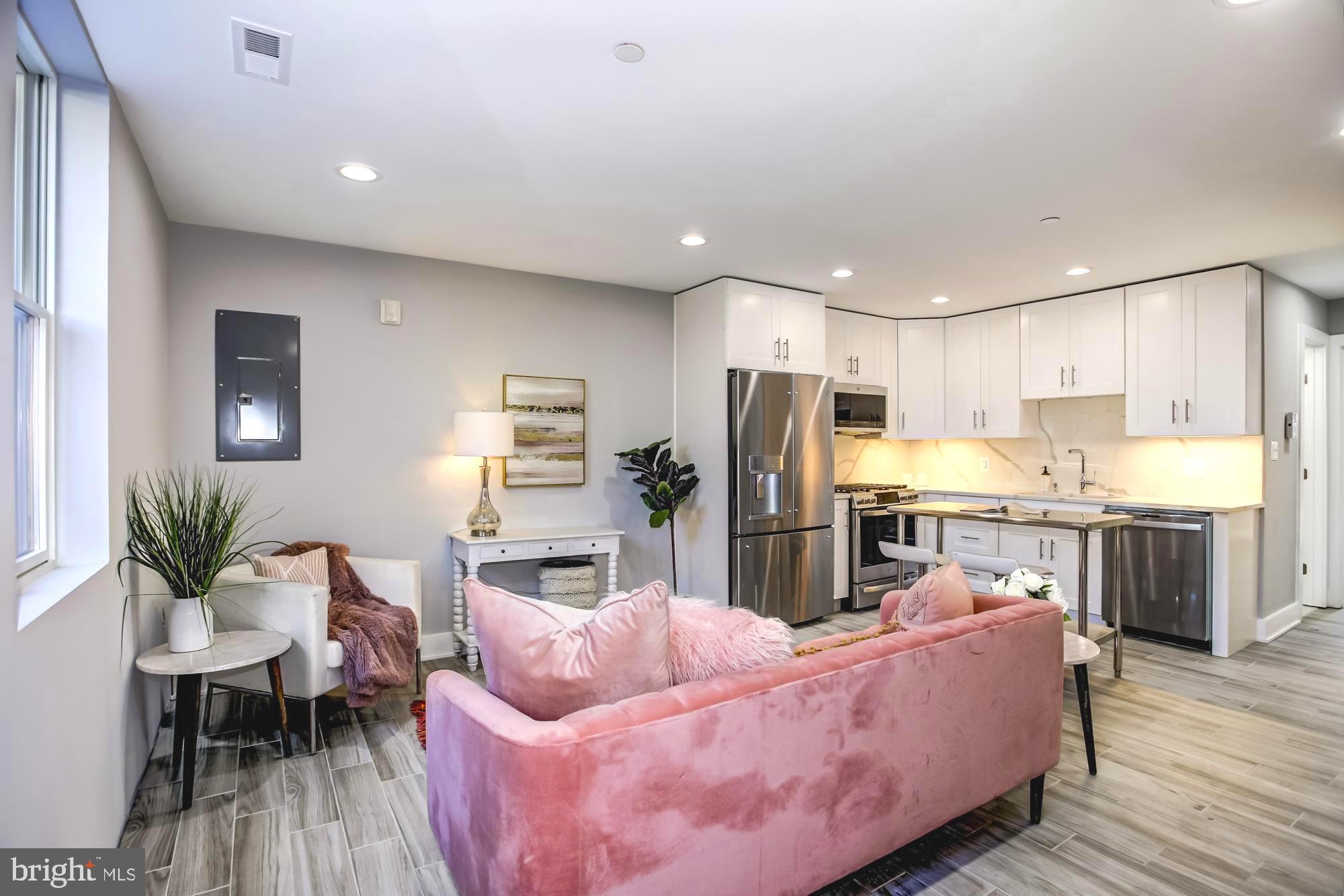 a living room with stainless steel appliances kitchen island granite countertop furniture and wooden floor