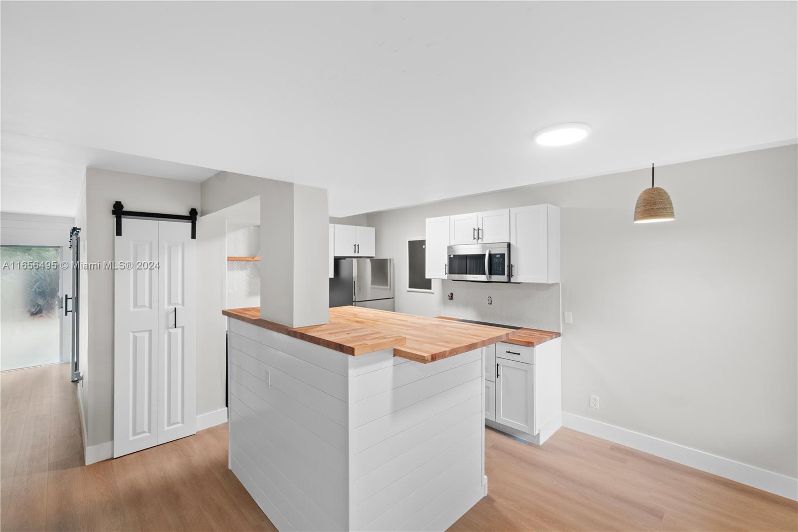 a room with wooden floor and white cabinets