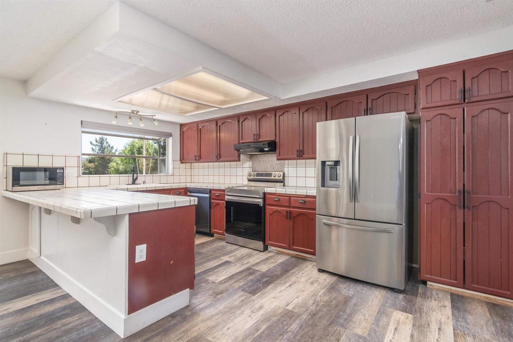 a kitchen with stainless steel appliances granite countertop a refrigerator a sink dishwasher a stove with wooden floors