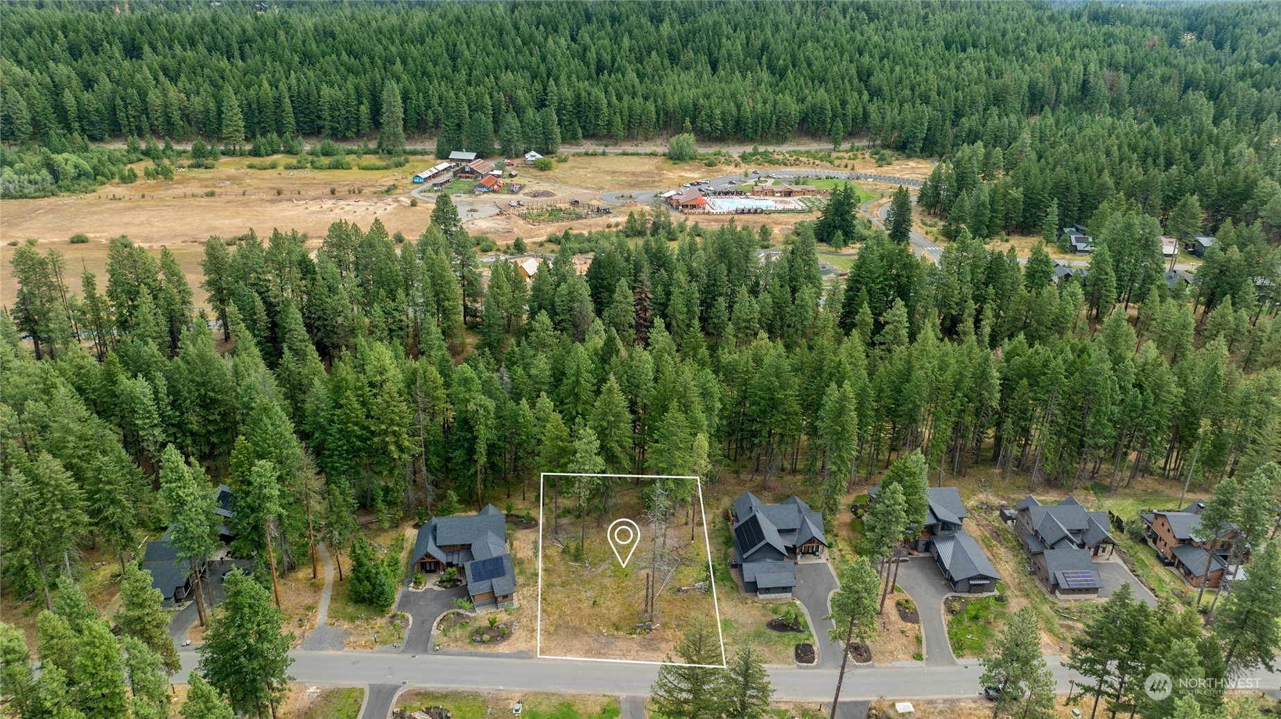 an aerial view of residential house with outdoor space and trees all around