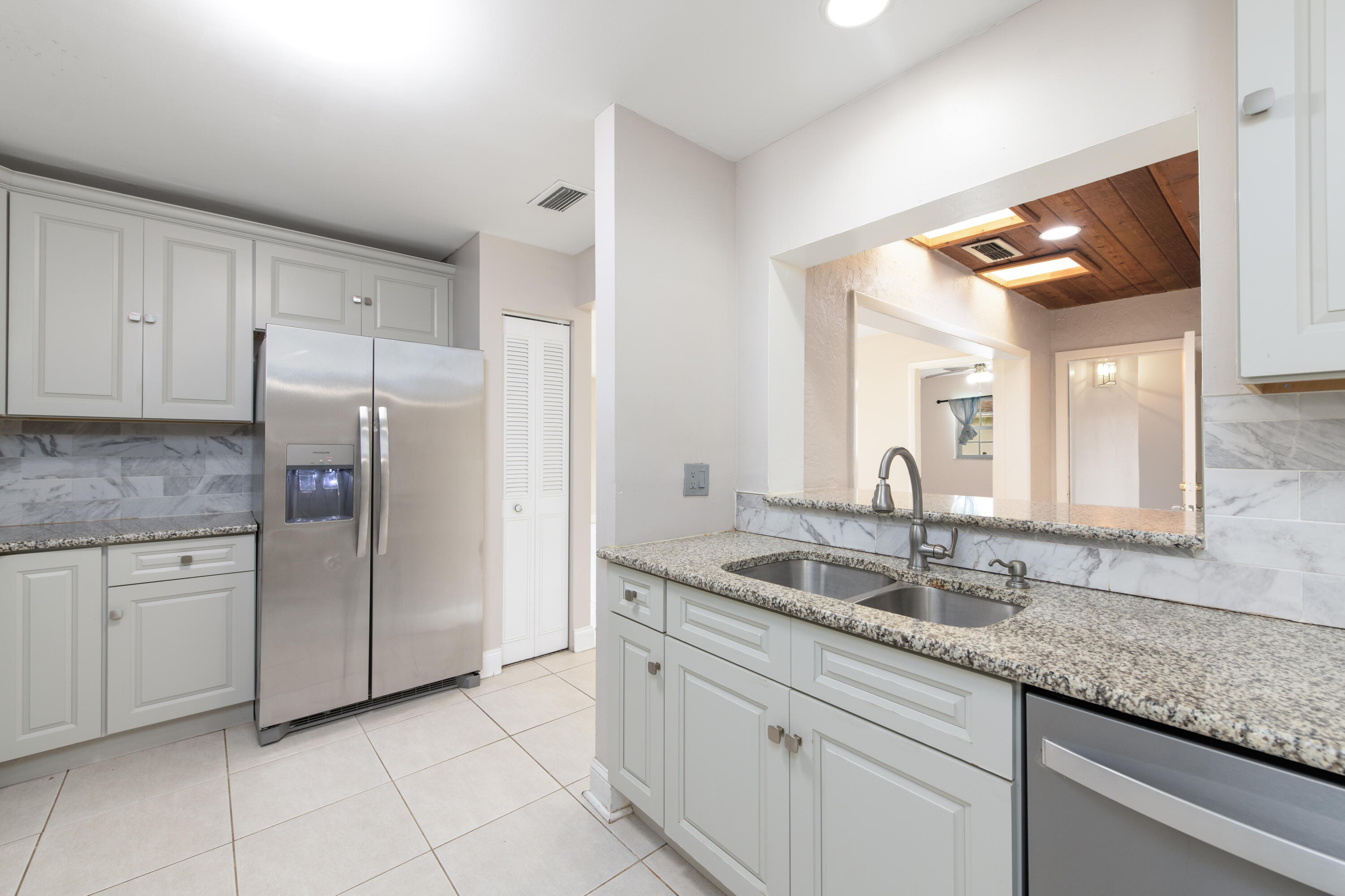 a kitchen with stainless steel appliances granite countertop a sink and dishwasher a refrigerator with white cabinets