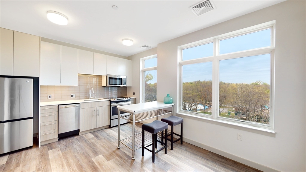 a kitchen with a table chairs refrigerator and wooden floor