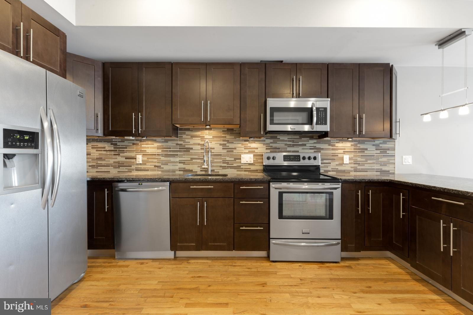 a kitchen with stainless steel appliances granite countertop a stove microwave and refrigerator