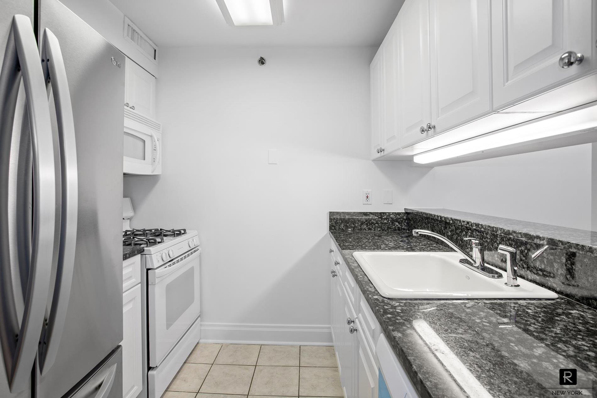 a kitchen with granite countertop a sink stove and refrigerator