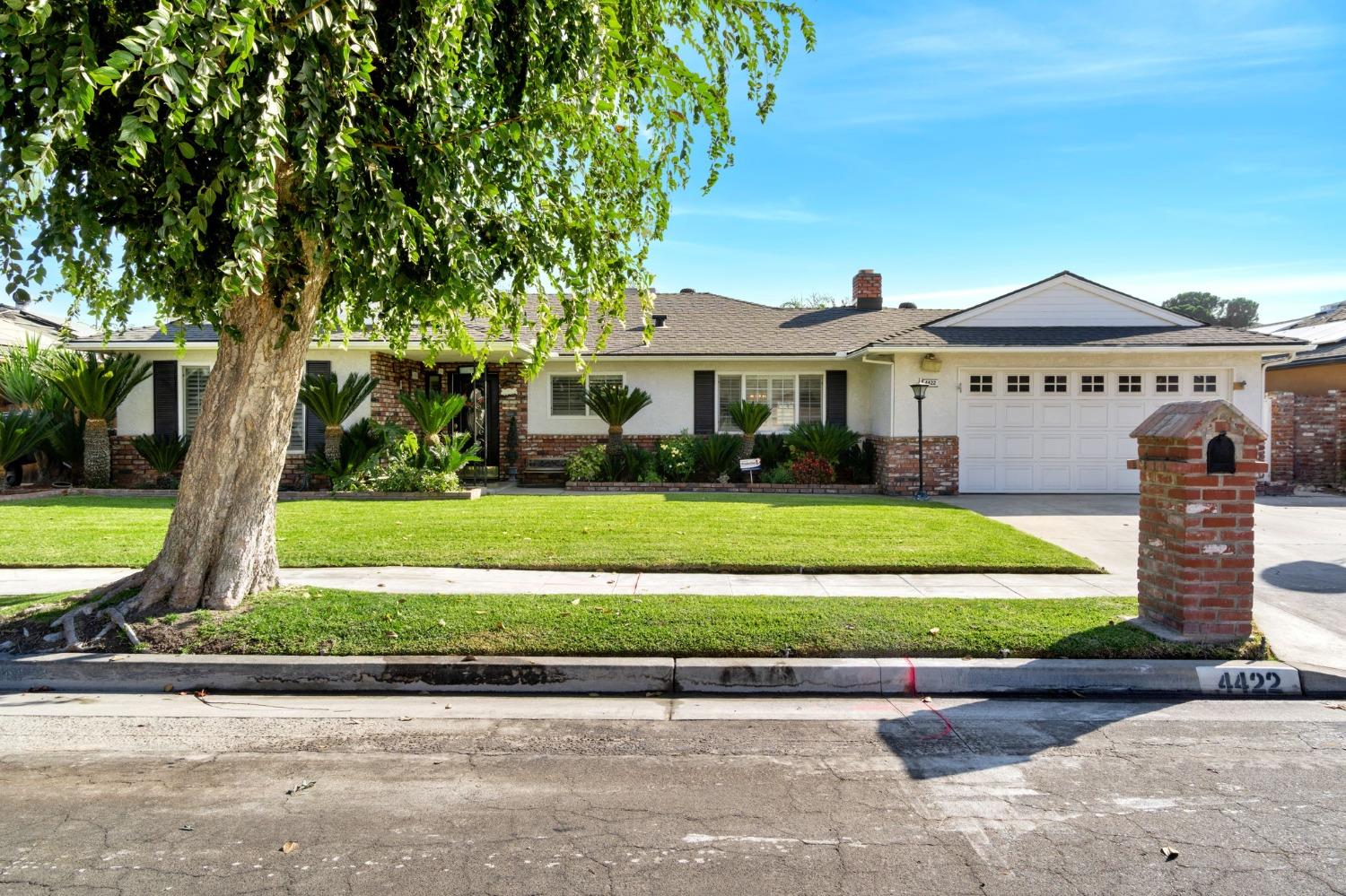 a front view of a house with a garden and trees