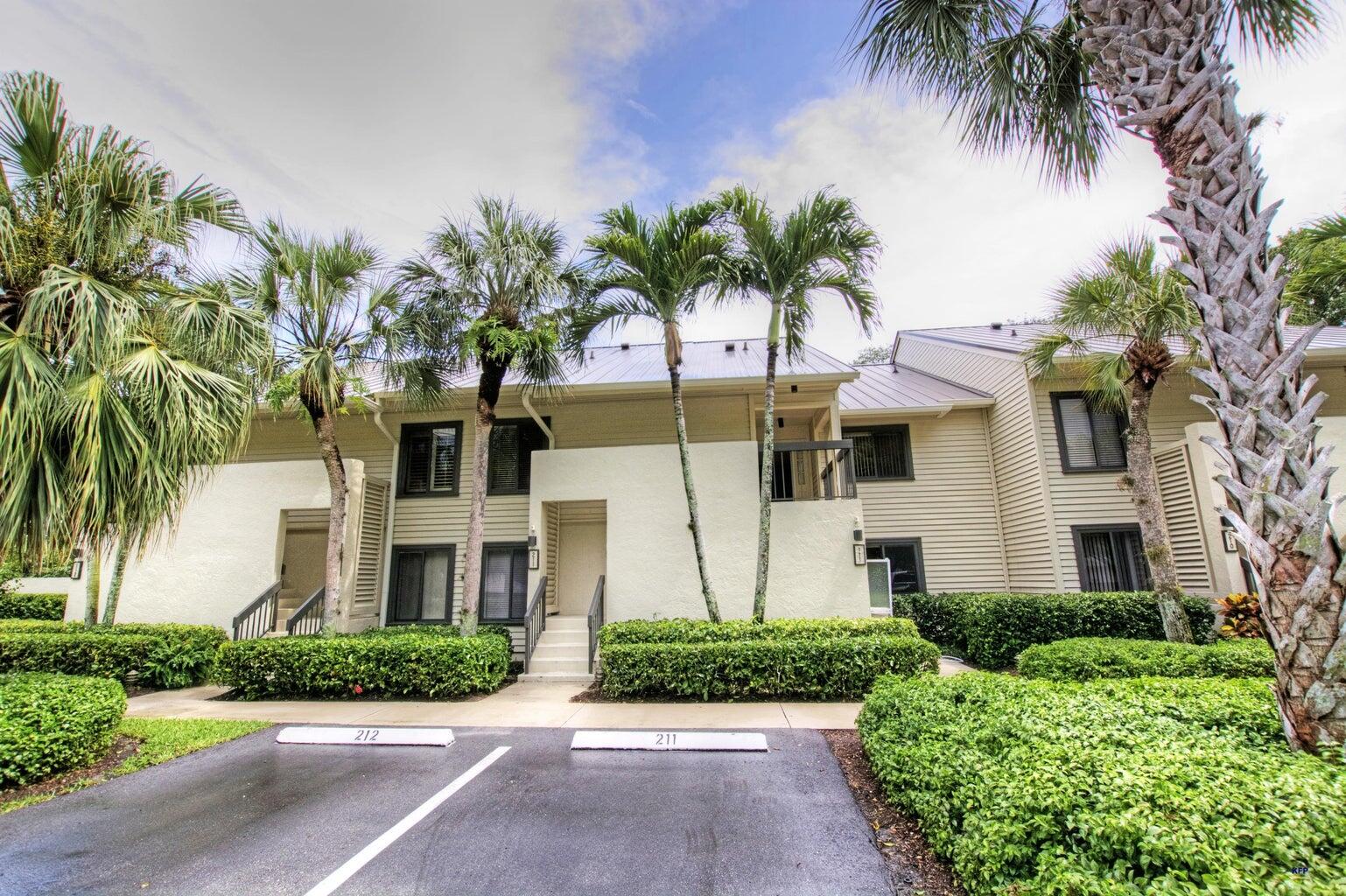 a front view of multi story residential apartment building with yard and green space