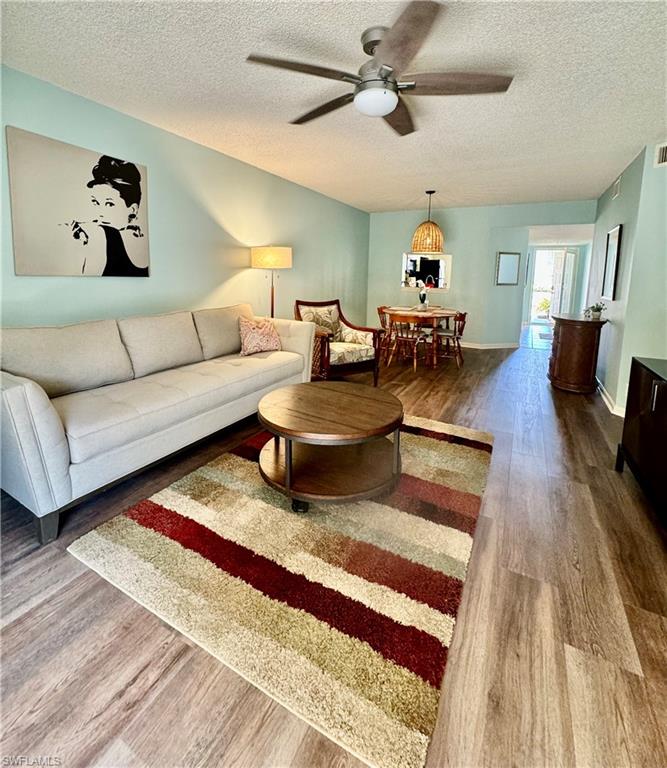 Living room with ceiling fan, dark hardwood / wood-style flooring, and a textured ceiling