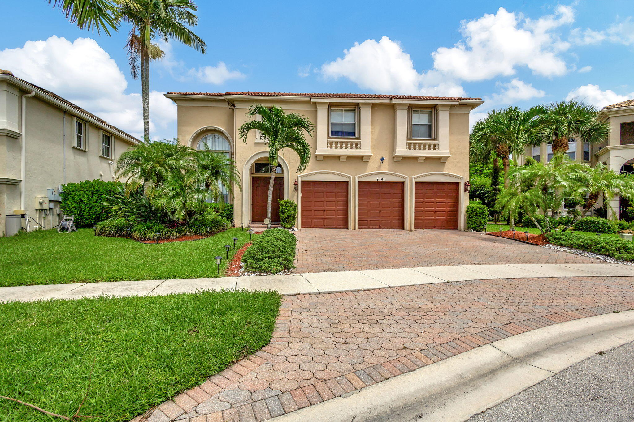 a front view of a house with a garden and palm tree