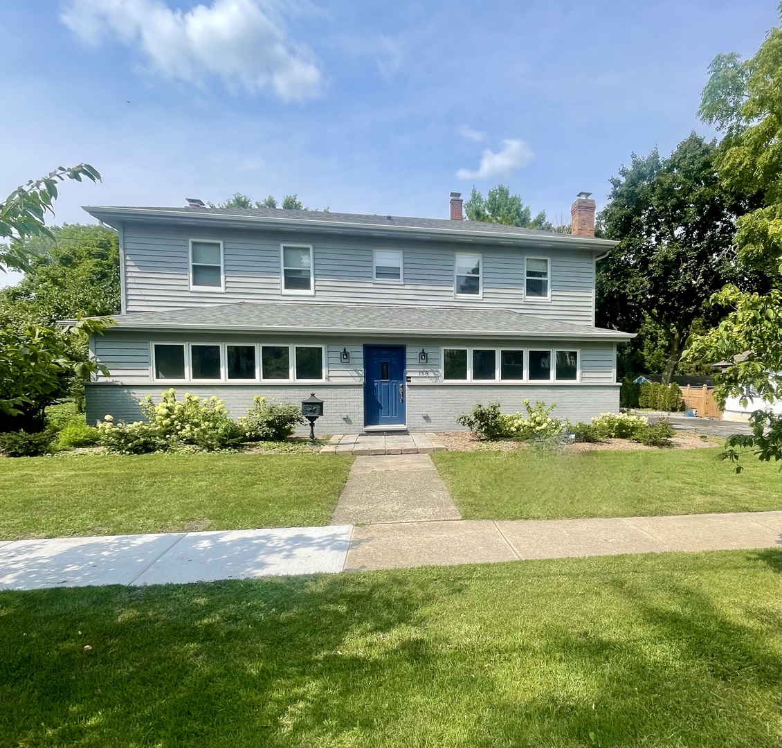 a front view of a house with a yard and trees