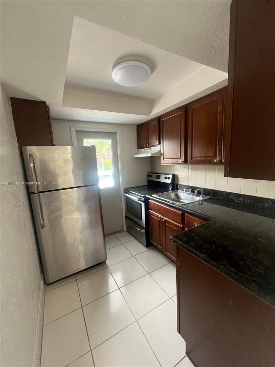 a kitchen with stainless steel appliances granite countertop a stove a sink and a refrigerator