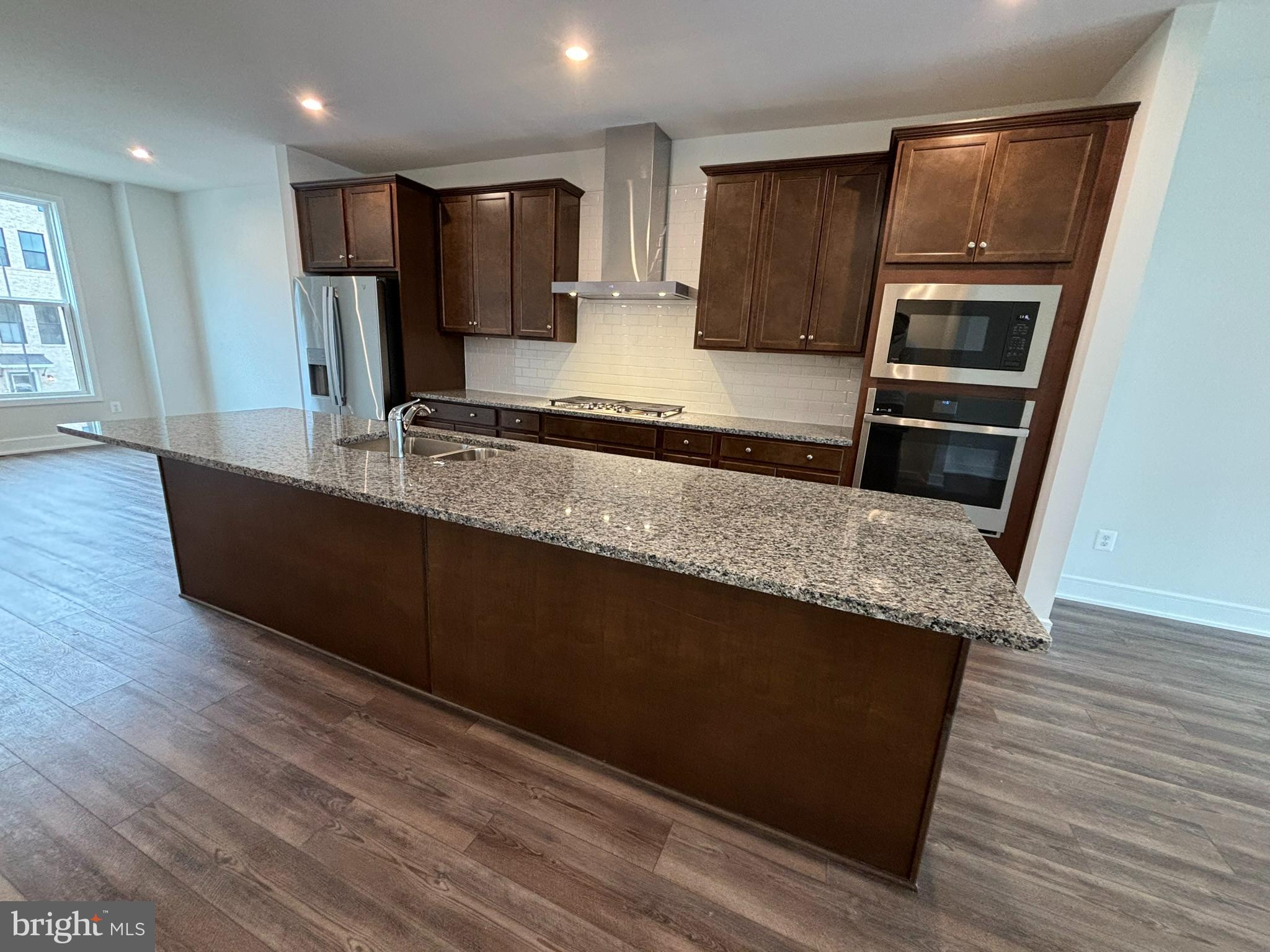 a large kitchen with wooden floors and stainless steel appliances