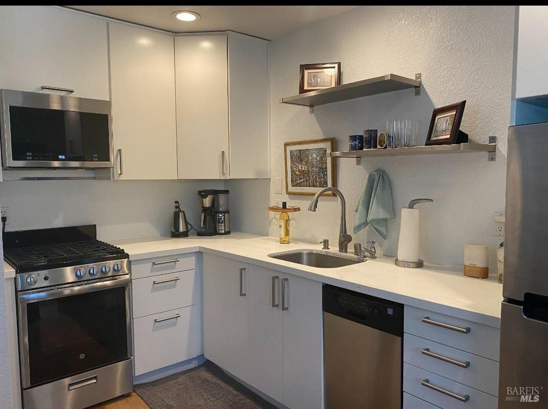 a kitchen with stainless steel appliances a sink stove and microwave