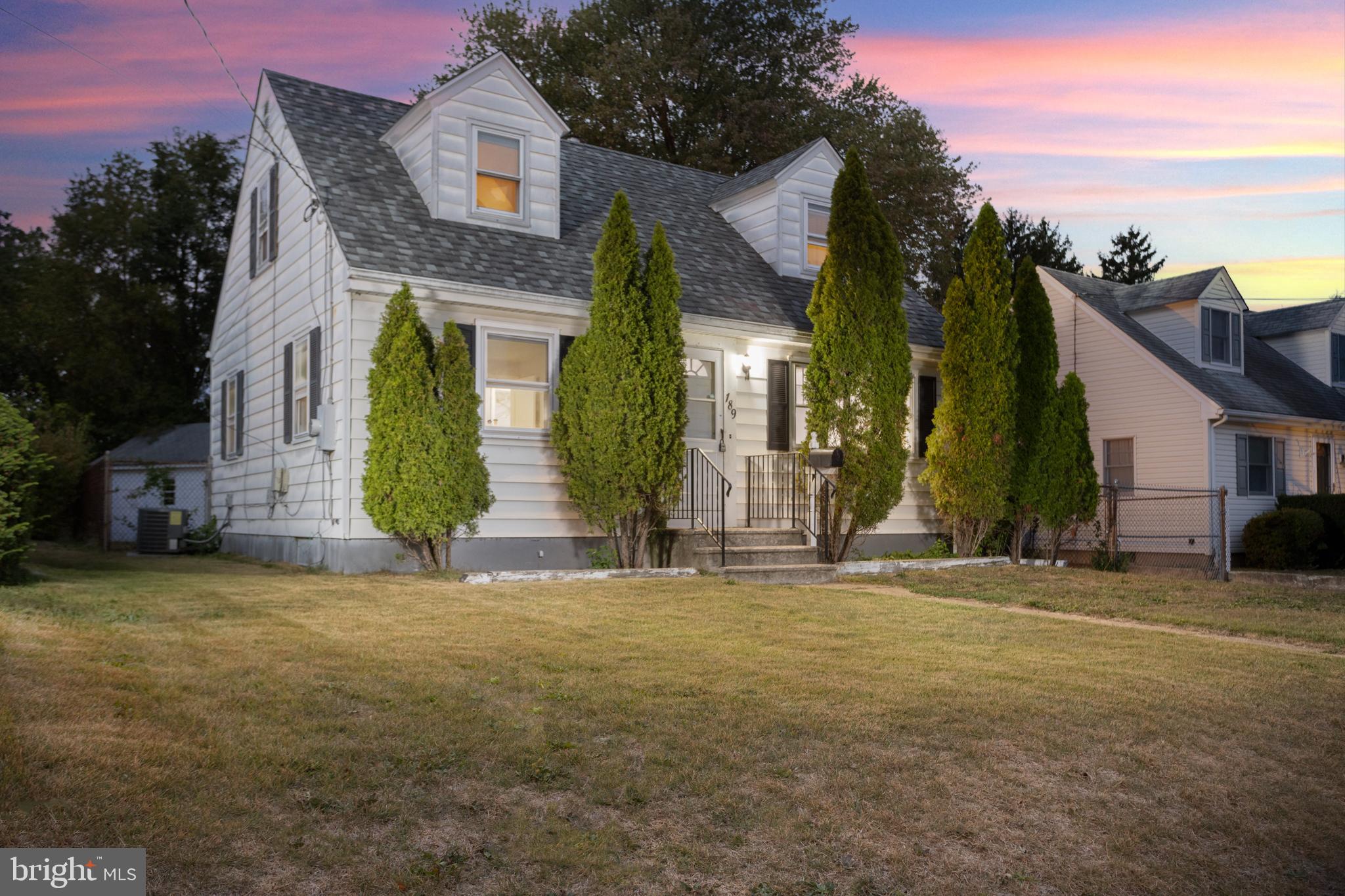 a view of a brick house with a big yard and large trees