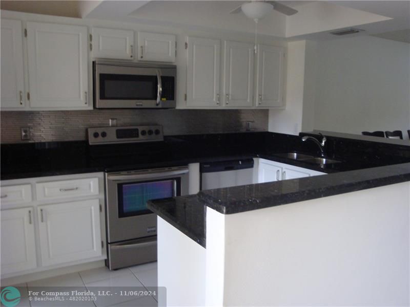 a kitchen with granite countertop white cabinets and black appliances