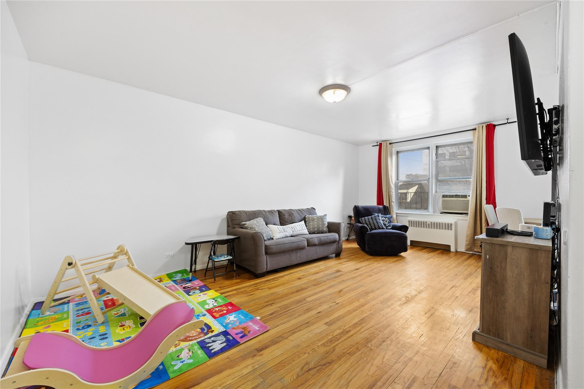 Recreation room with radiator heating unit and wood-type flooring