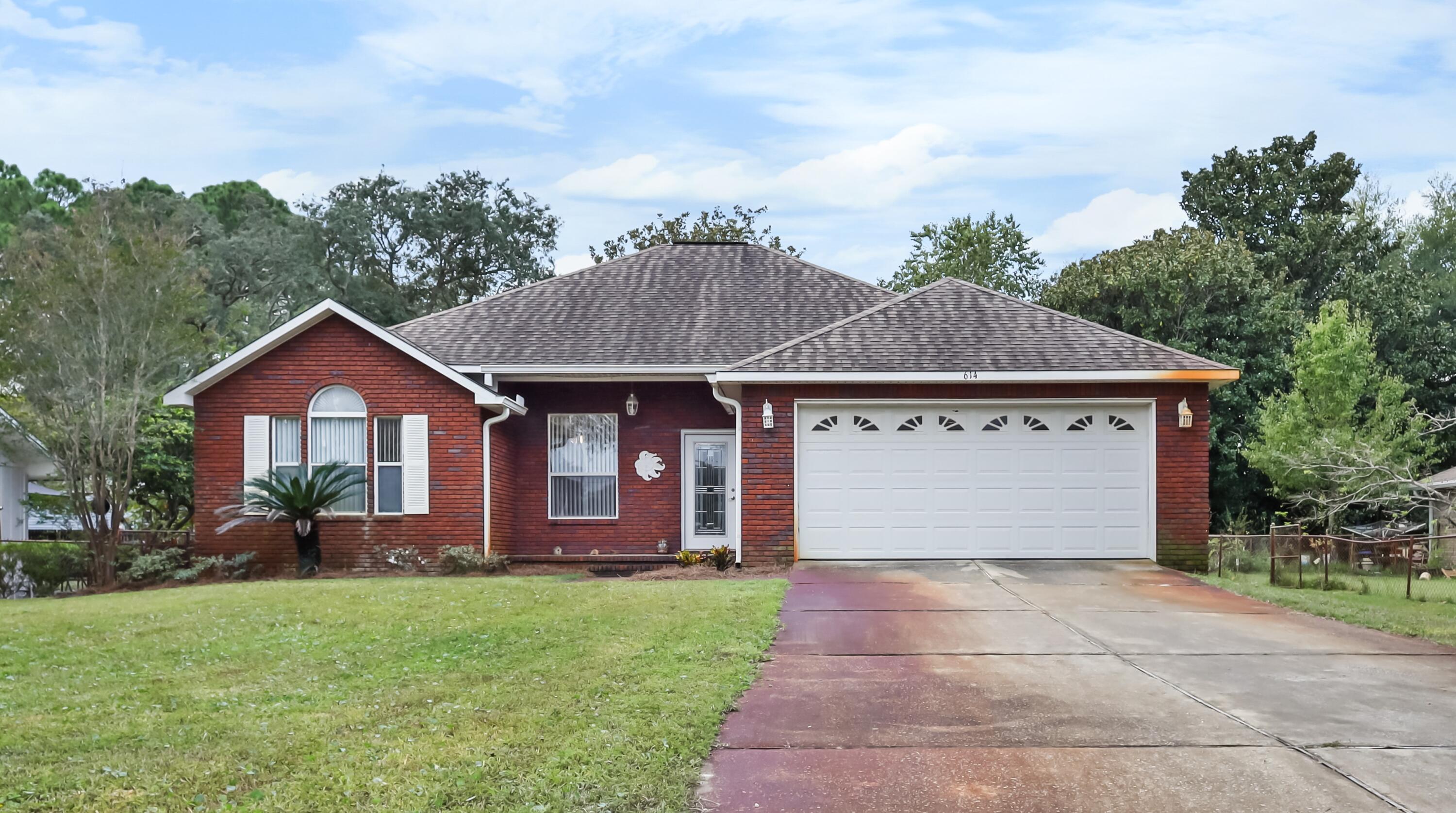 a front view of house with yard and trees in the background