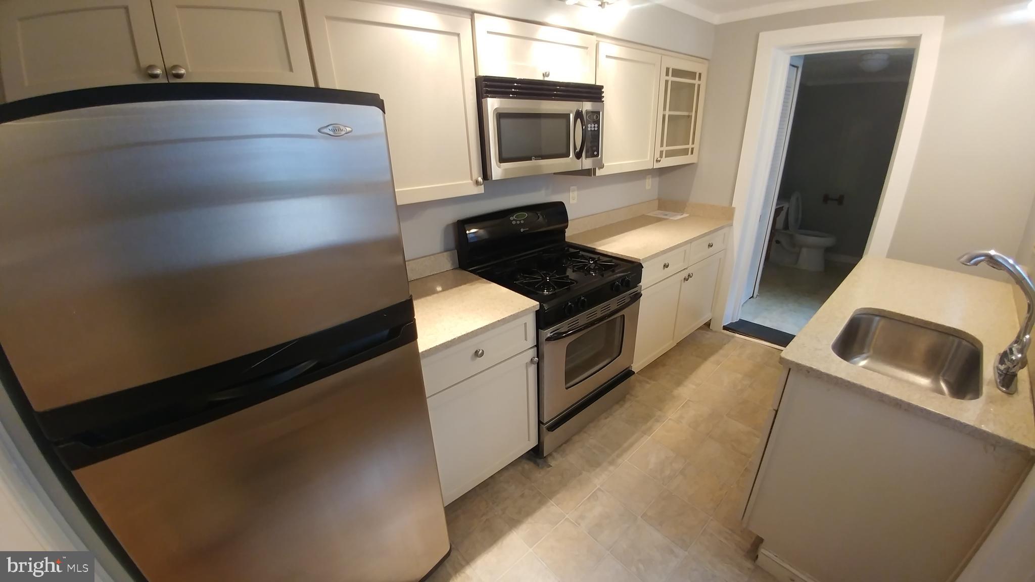 a kitchen with granite countertop a sink a stove top oven and refrigerator