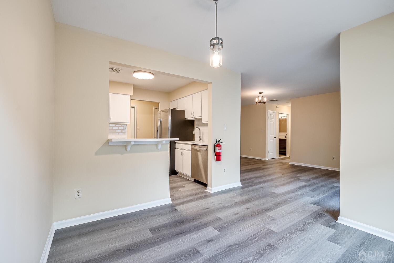 a view of a kitchen and an empty room with wooden floor