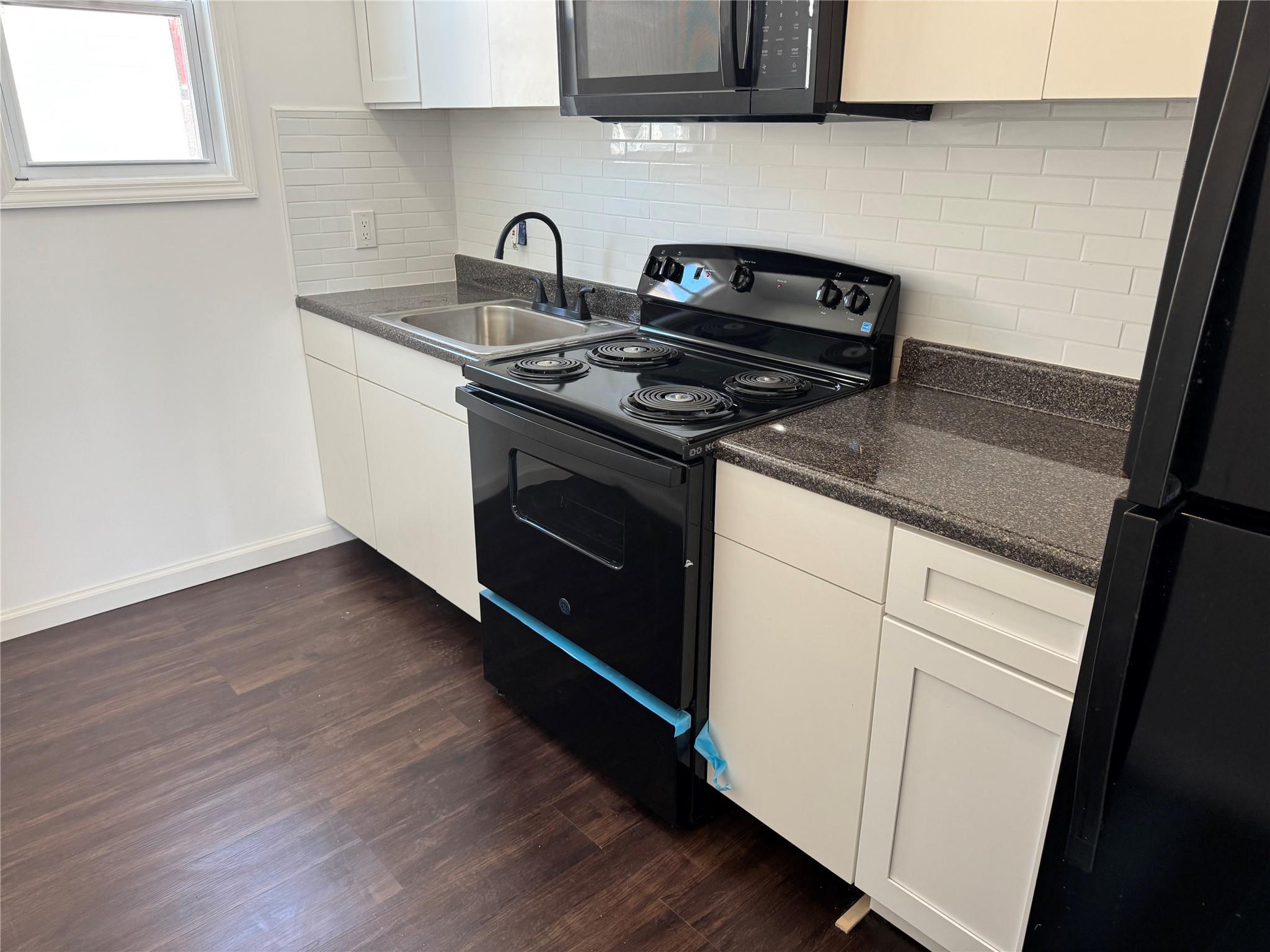 a kitchen with granite countertop wooden cabinets stove and sink