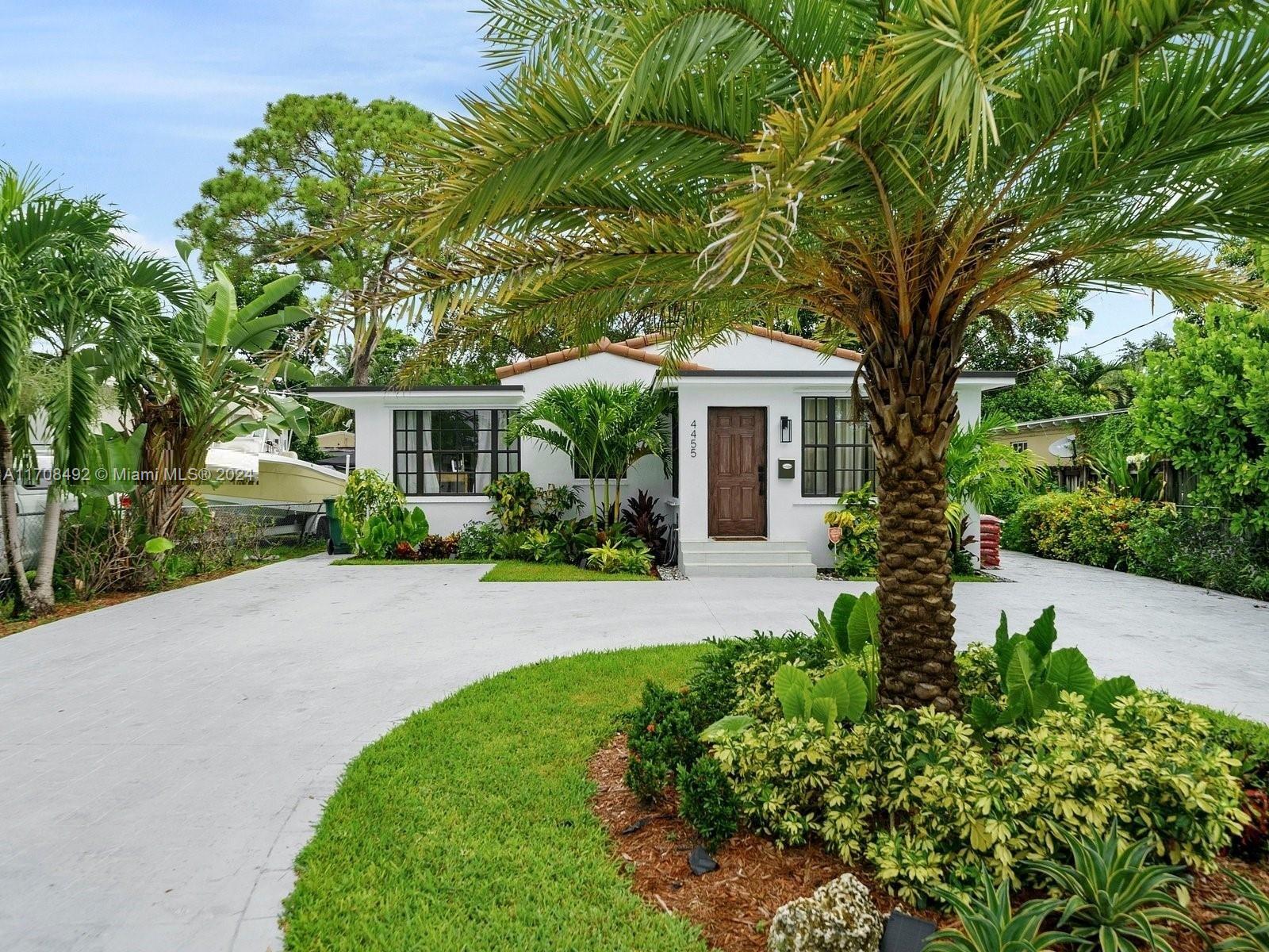 a front view of a house with a yard and potted plants