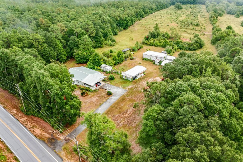 an aerial view of residential house with outdoor space and trees all around