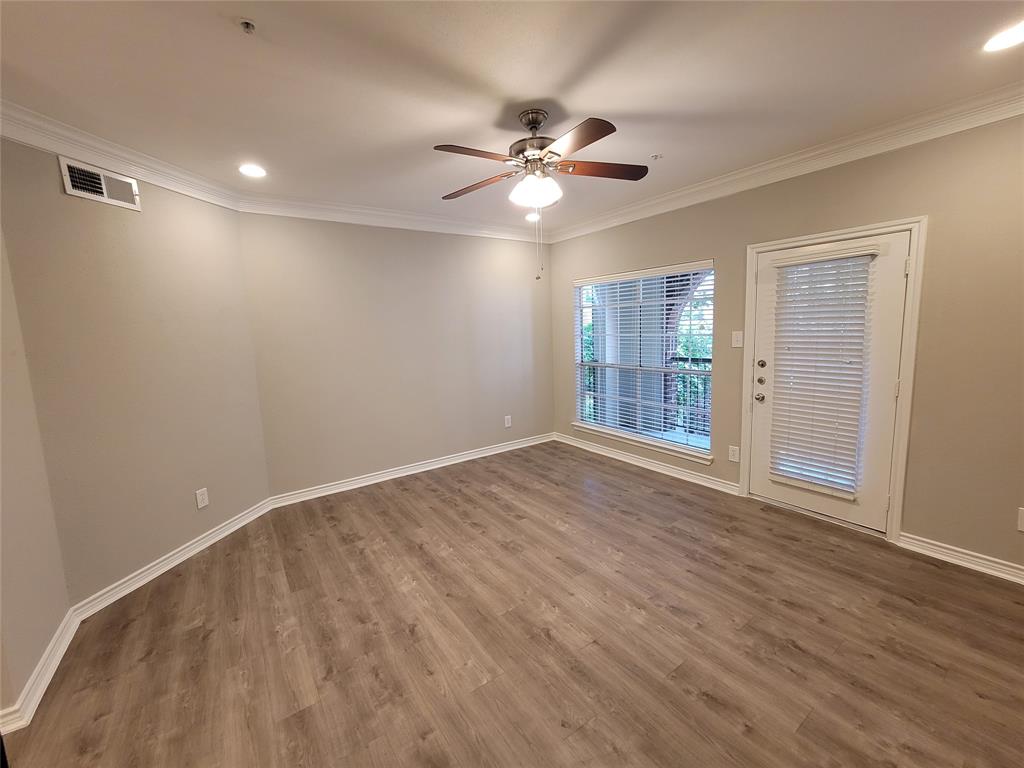 a view of an empty room with wooden floor and a ceiling fan