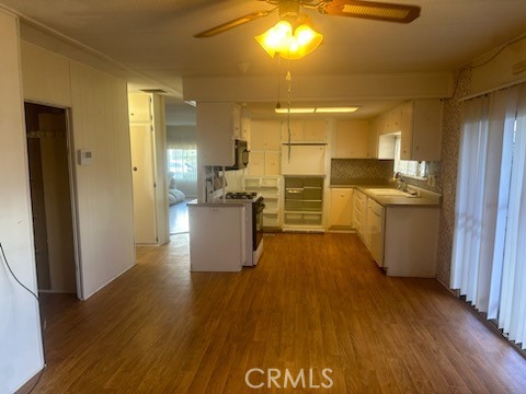 a view of a kitchen with kitchen island a sink wooden floor and stainless steel appliances