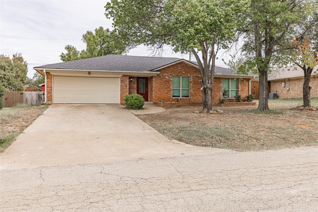 a front view of a house with a dirt yard and a large tree