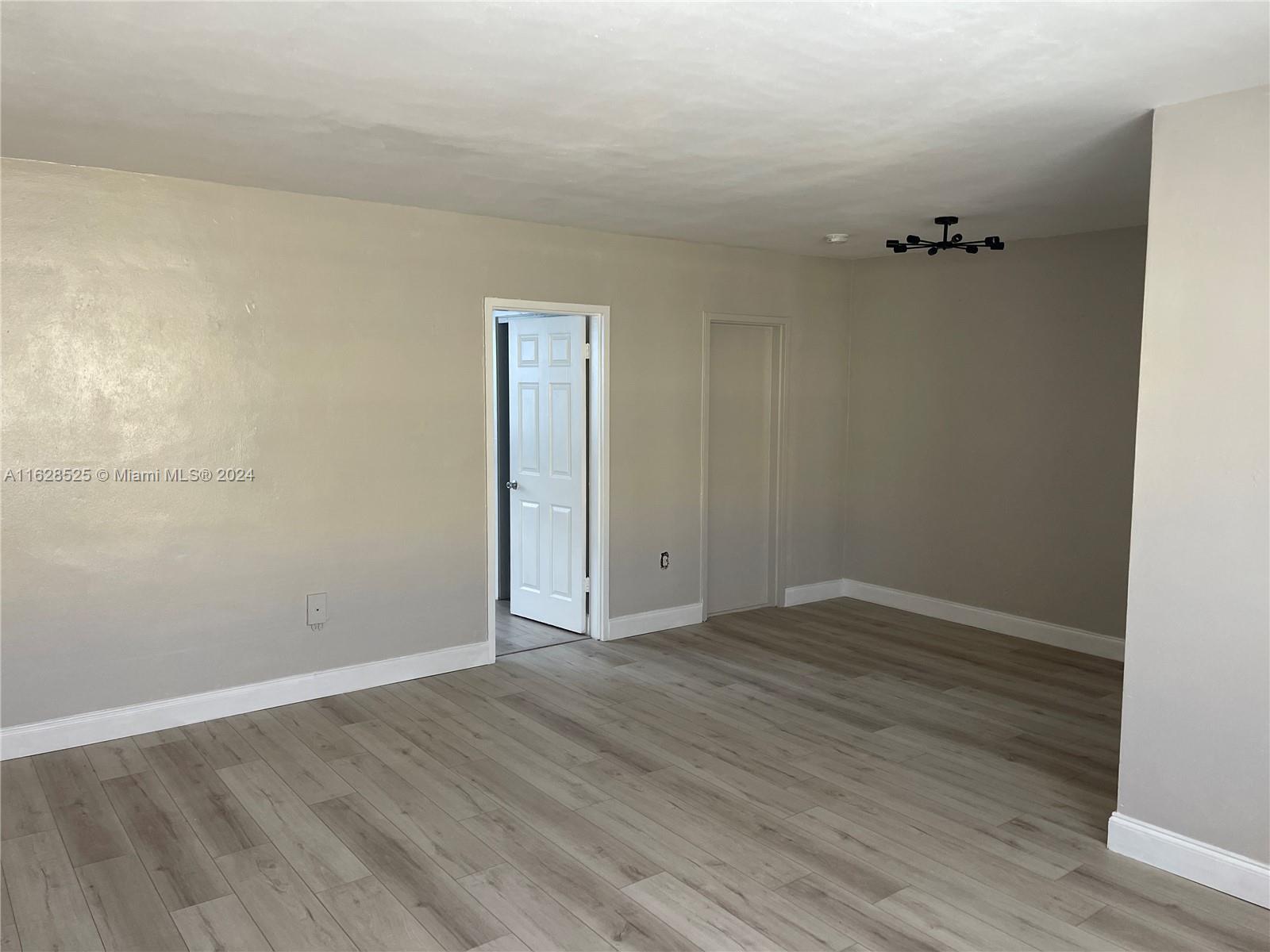 an empty room with wooden floor and bathroom