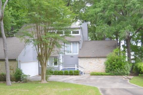 a front view of a house with a garden and tree