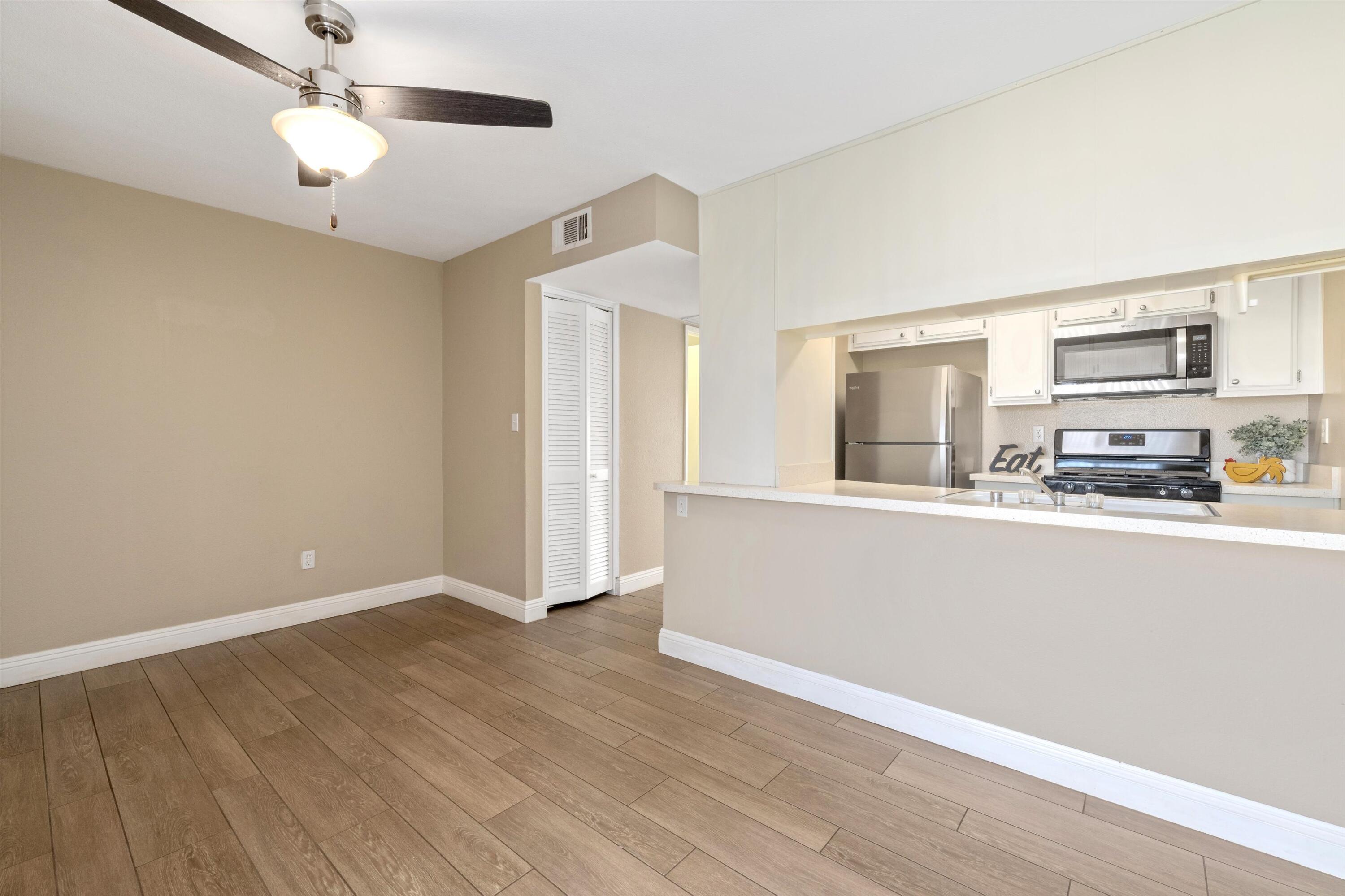 a view of a kitchen with wooden floor and a ceiling fan