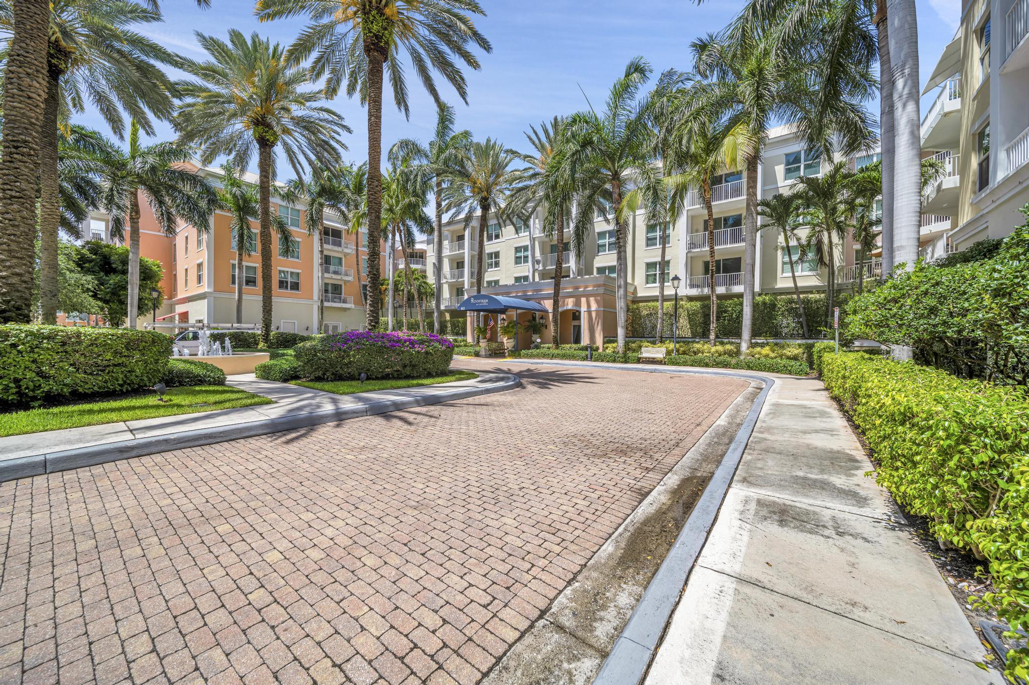 a view of multiple houses with a yard and palm trees