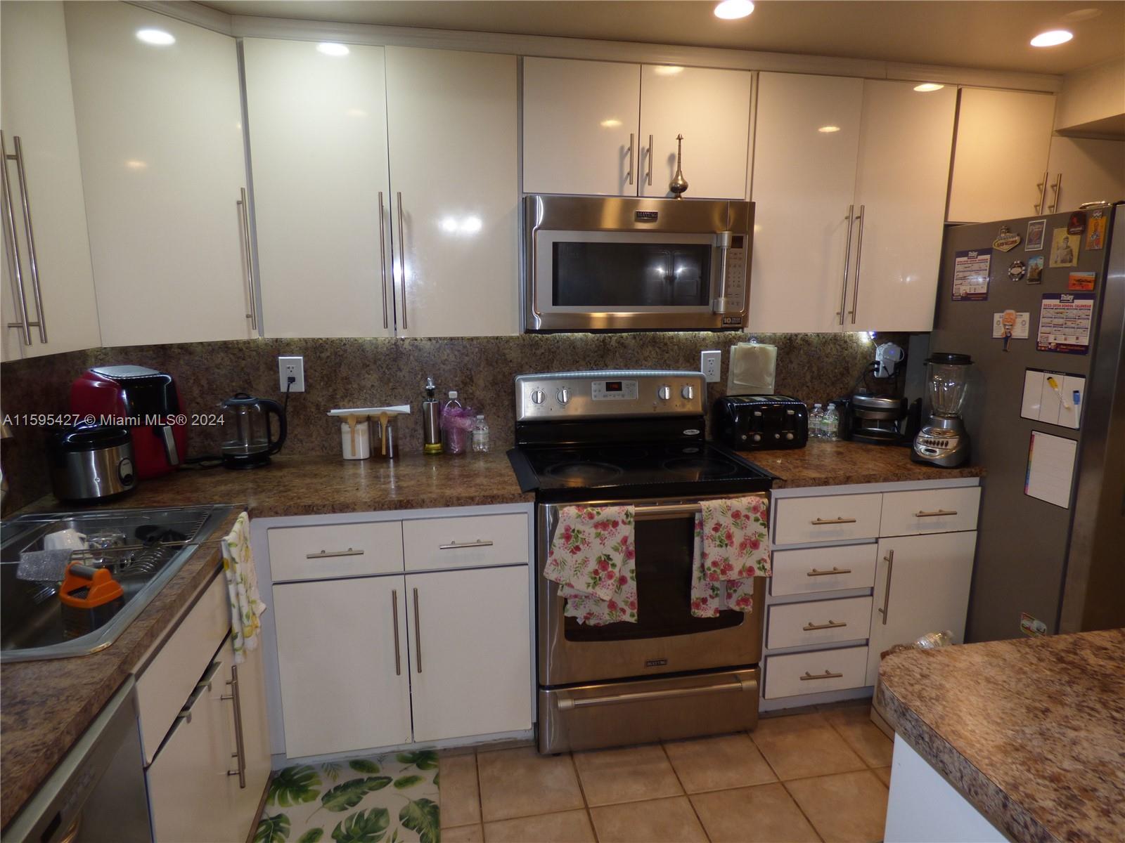 a kitchen with stainless steel appliances kitchen island granite countertop a stove a sink and a microwave