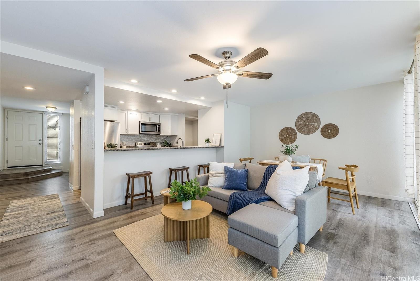 a living room with furniture kitchen view and a chandelier