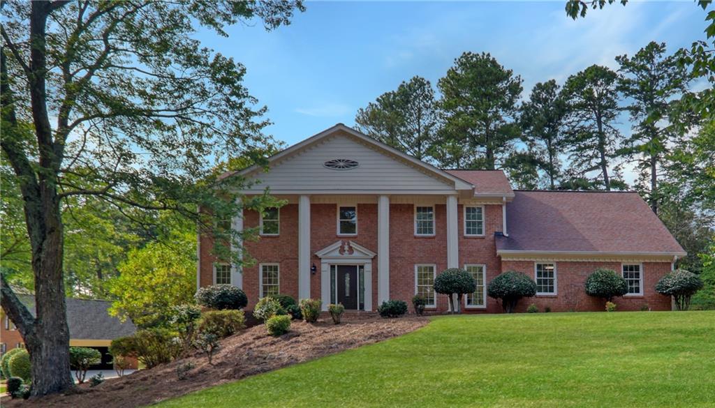 a front view of a house with a yard and large trees