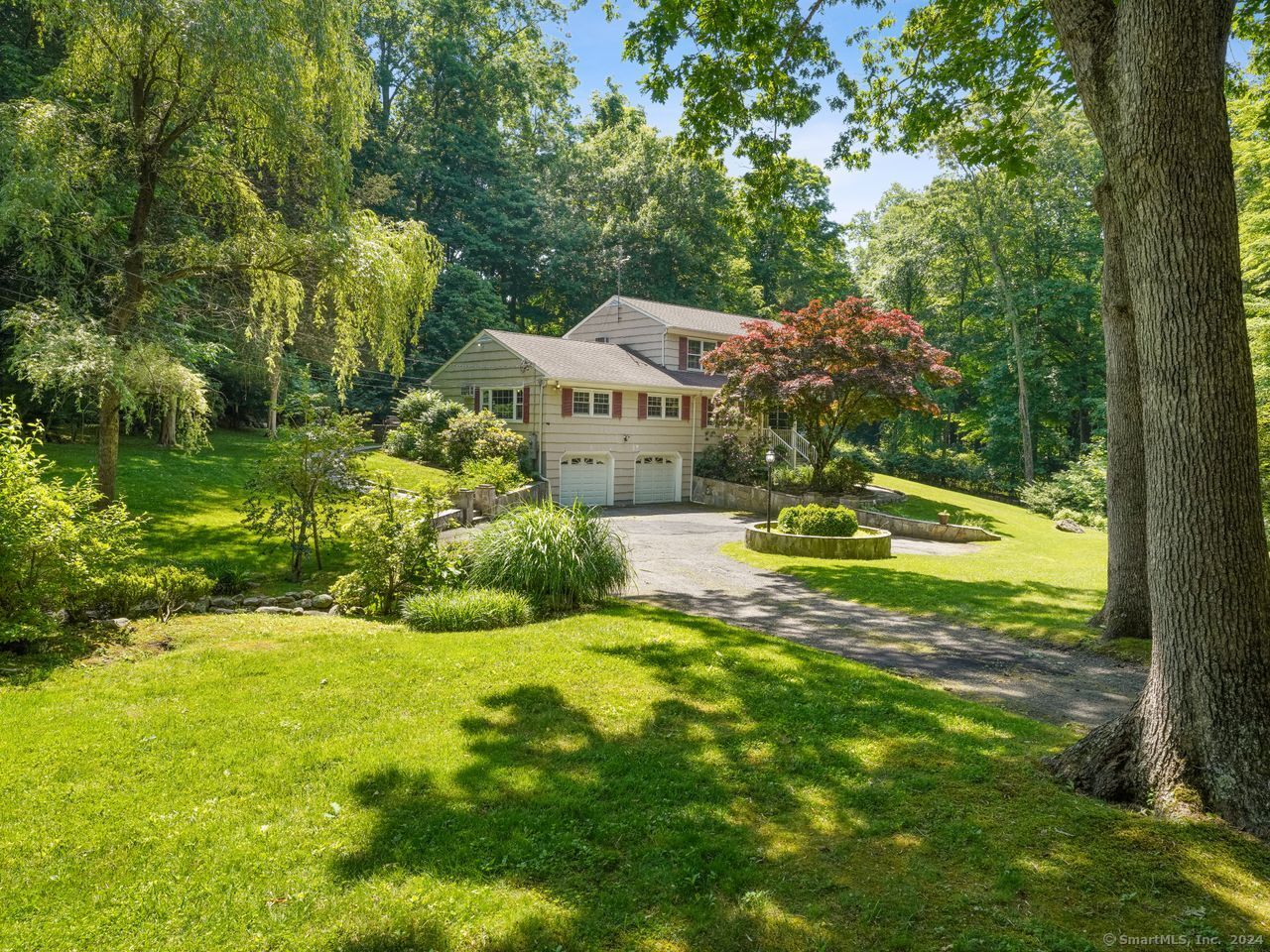 a view of a house with a big yard and large trees