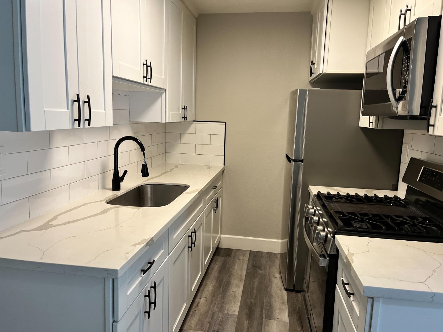 a kitchen with stainless steel appliances granite countertop a sink stove and refrigerator