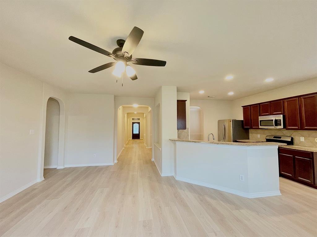 a living room with stainless steel appliances kitchen island a flat screen tv and a refrigerator