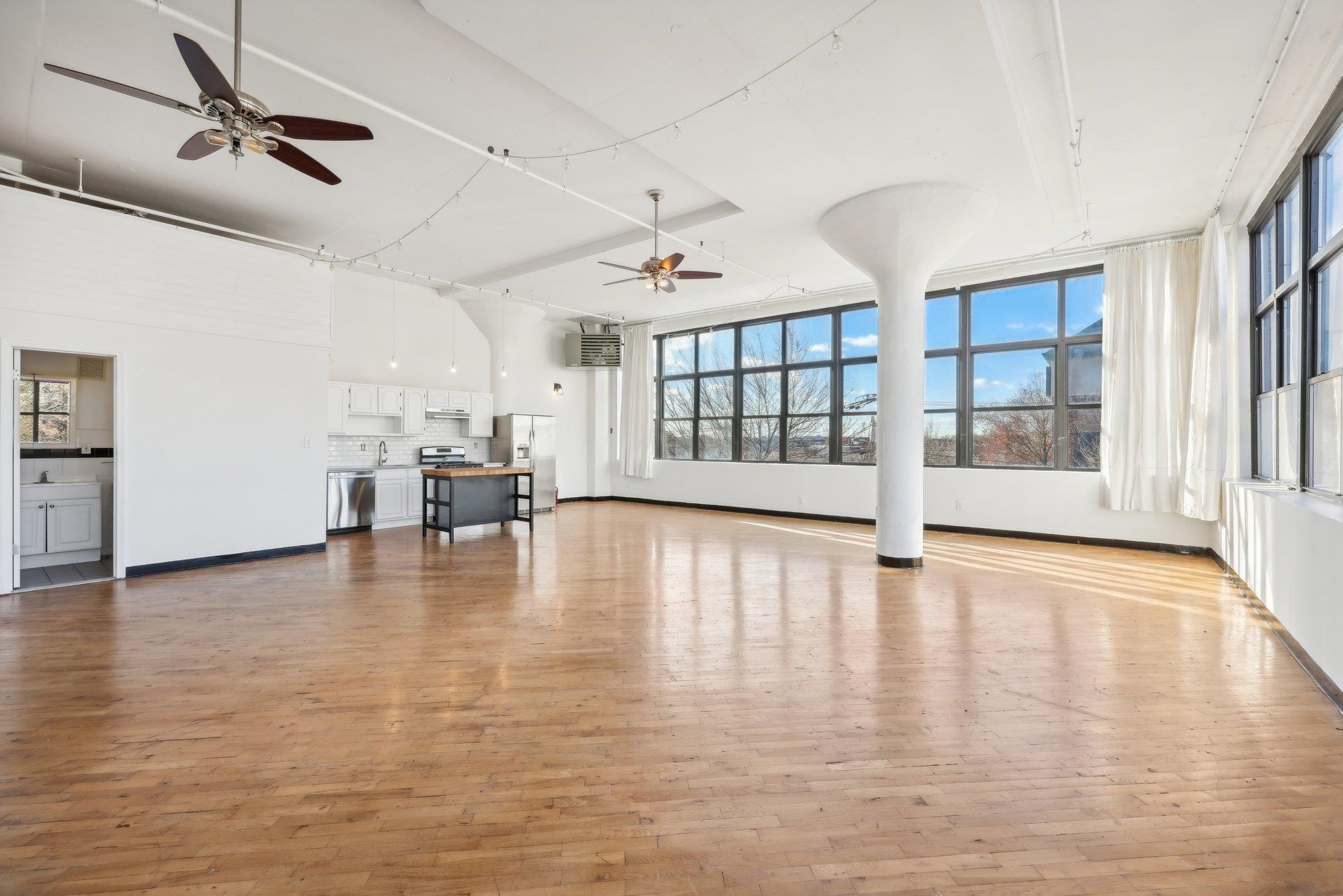 a view of an empty room with a window and wooden floor