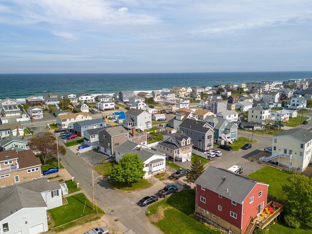 an aerial view of a city with lots of residential buildings and ocean view in back