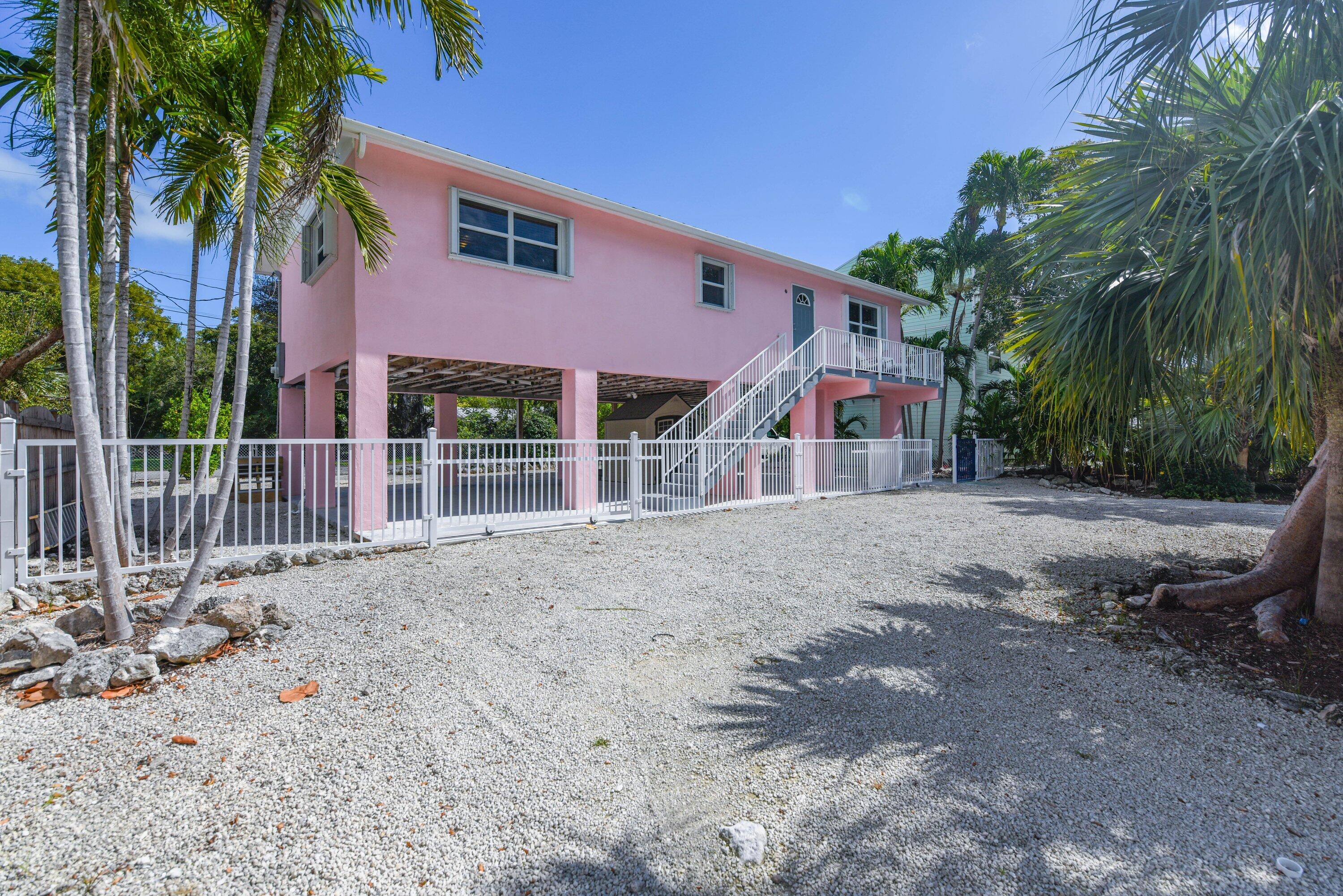 a view of a white house with a yard and palm trees