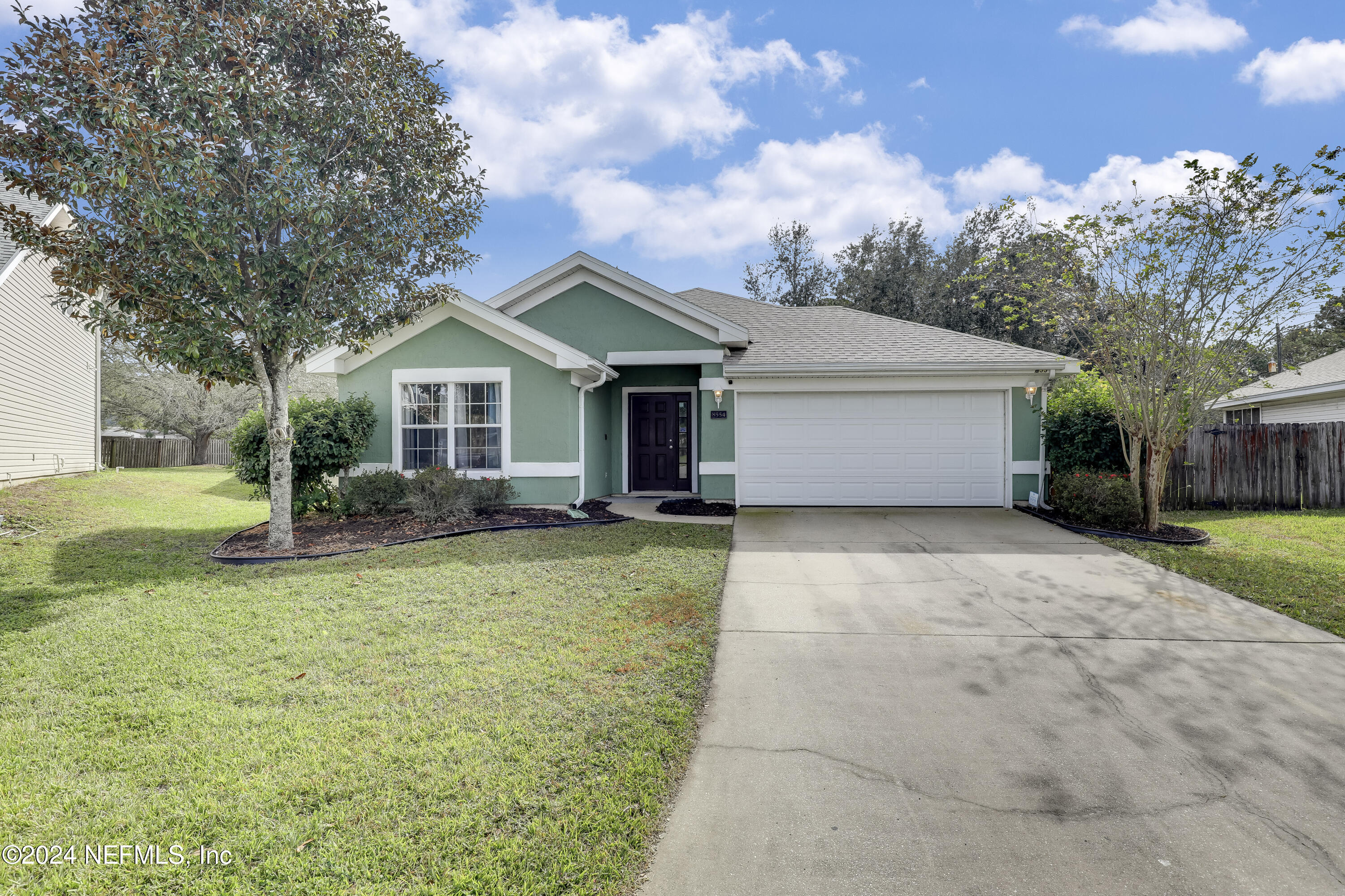 a front view of house with yard and trees in the background