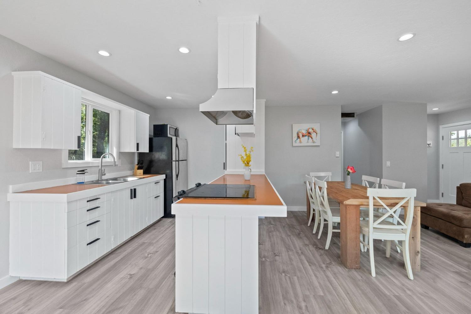 a kitchen with stainless steel appliances kitchen island granite countertop a table chairs sink and cabinets