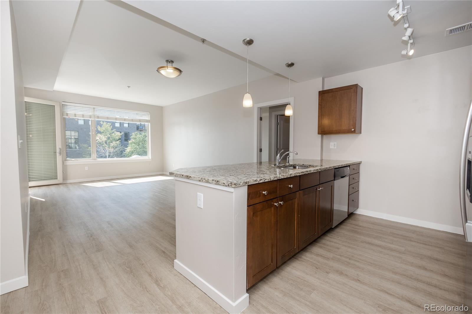 a large kitchen with stainless steel appliances granite countertop a sink and a wooden floor