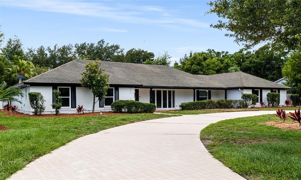 a front view of a house with a garden and trees