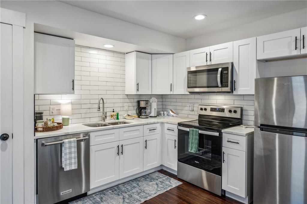 a kitchen with cabinets stainless steel appliances a sink and wooden floor