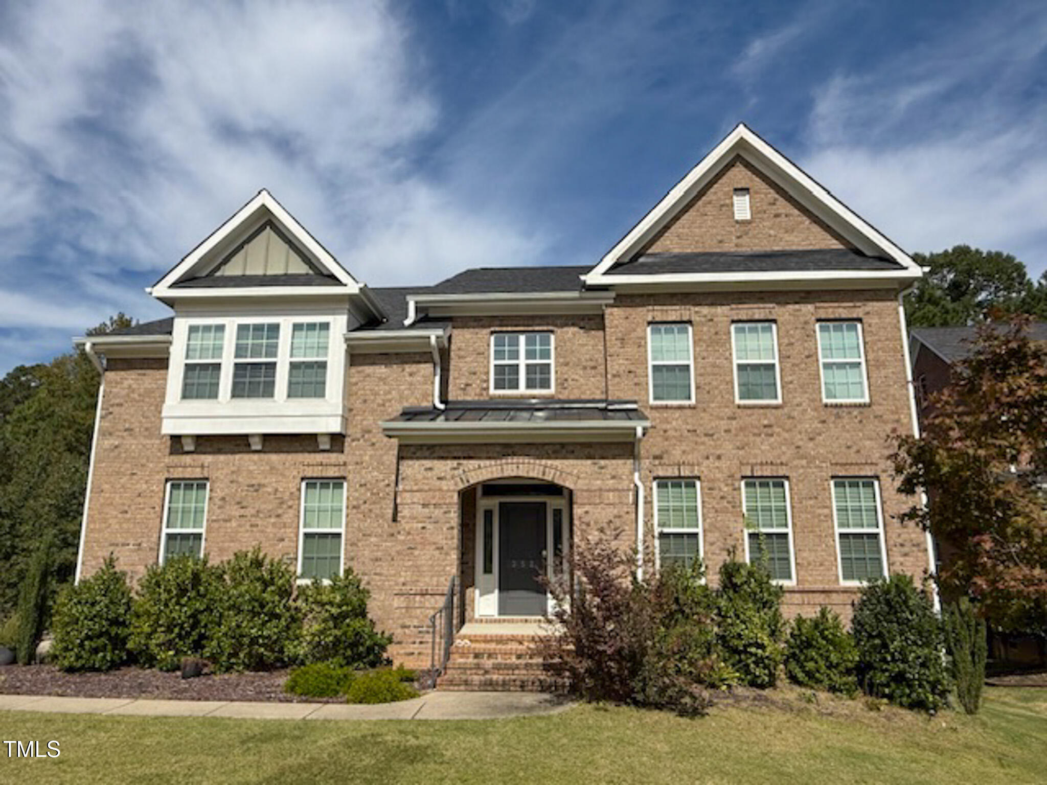 a front view of a house with yard and green space