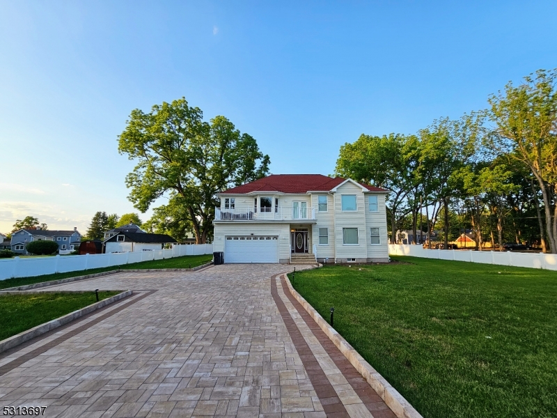 a view of a white house next to a yard with big trees